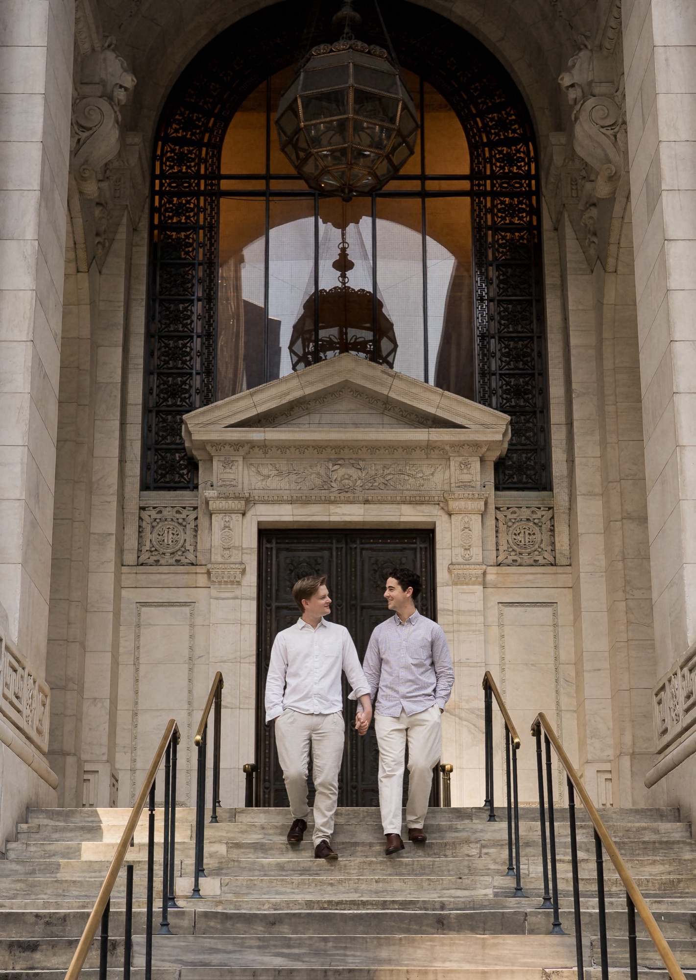 Lach and Bryce walking down marble steps, holding hands