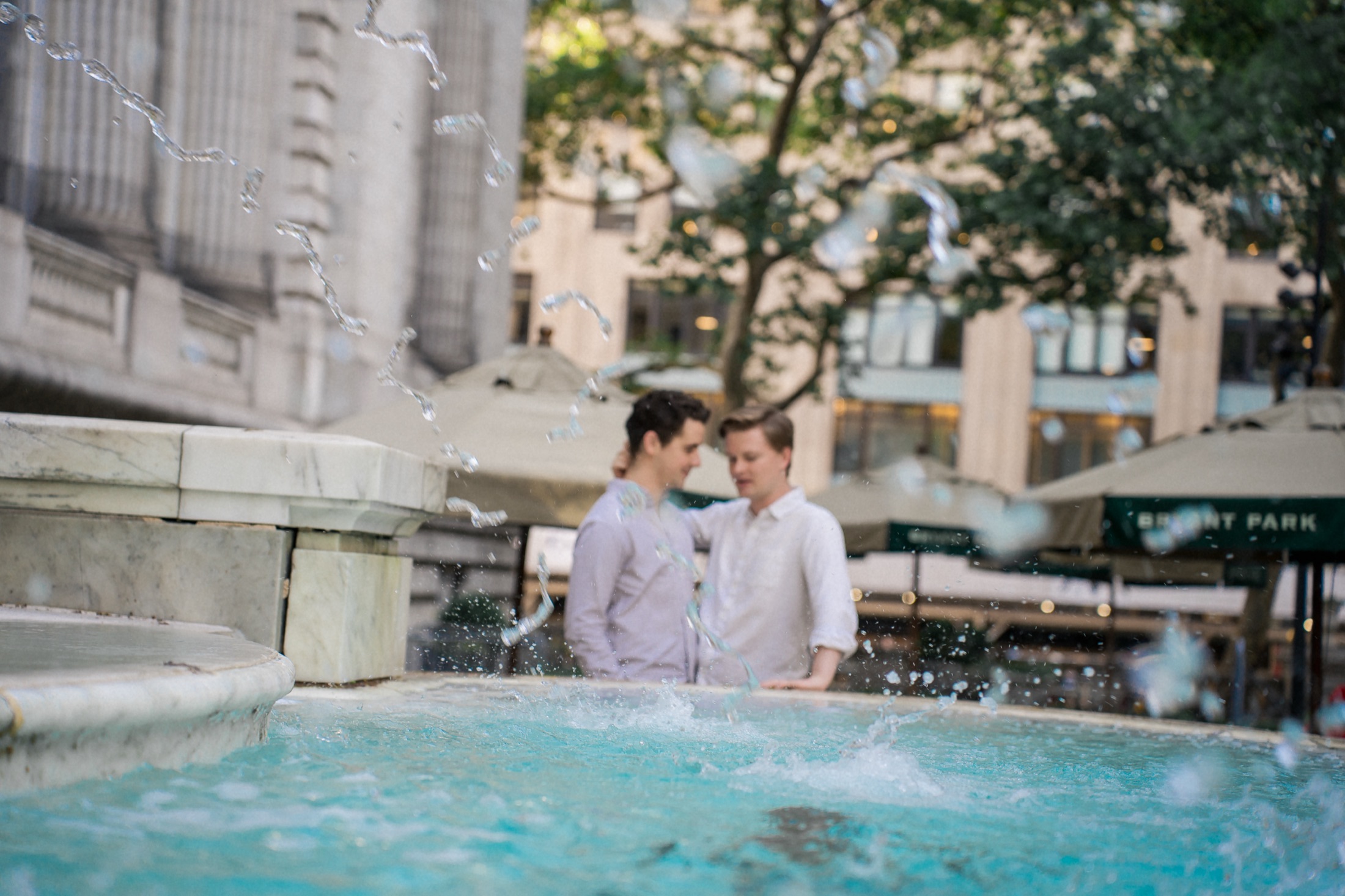 Lach and Bryce standing together beside a fountain by the New York Public Library